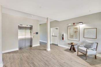 A room with a chair, a table, and a painting on the wall.